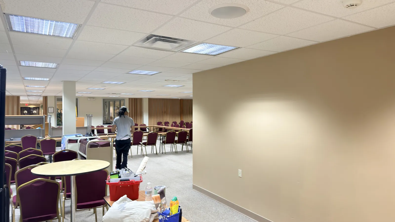 A commercial meeting room mid-repaint, with wall surfaces prepared and floors protected